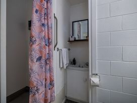 A bathroom with a shower curtain and sink at Te Tiriti Beach House - Paihia Holiday Home