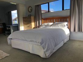 A bedroom with a bed and dresser at Jack and Enid’s Whangamata Beach House Whangamata