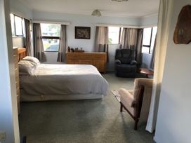 A bedroom with a bed and seating area at Jack and Enid’s Whangamata Beach House in Whangamata