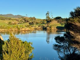A scenic view of a lake surrounded by trees and hills at Sunset Stay - Raglan Holiday Home, Raglan
