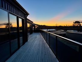 A deck with railing and buildings at Sunset Stay - Raglan Holiday Home, Raglan