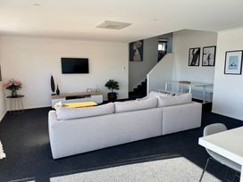 A living room with a television and sofa at Sunset Stay - Raglan Holiday Home in Raglan