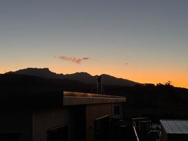 A silhouette of mountains and buildings at sunset at Sunset Stay - Raglan Holiday Home, Raglan