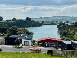 A view of houses and a boat near the water at Sunset Stay - Raglan Holiday Home Raglan