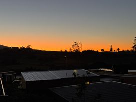 A sunset view over houses and trees at Sunset Stay - Raglan Holiday Home in Raglan