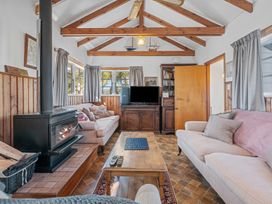 A living room with two sofas a wooden coffee table a wood stove and a television at Okere Retreat - Lake Rotoiti Getaway Lake Rotoiti