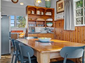 A wooden dining table with blue chairs and a ceramic bowl in a kitchen with wooden cupboards and shelves at Okere Retreat - Lake Rotoiti Getaway Lake Rotoiti