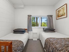 A bedroom with two single beds and a window showing trees at Okere Retreat - Lake Rotoiti Getaway