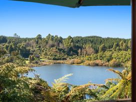 A view of a lake surrounded by trees and bushes under a clear blue sky at Okere Retreat - Lake Rotoiti Getaway