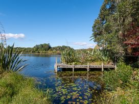 A wooden jetty surrounded by water lilies on a lake with trees and vegetation at Okere Retreat - Lake Rotoiti Getaway