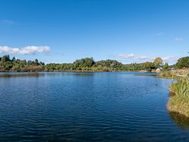 A lake with trees along the shore and a clear blue sky at Okere Retreat - Lake Rotoiti Getaway in Lake Rotoiti
