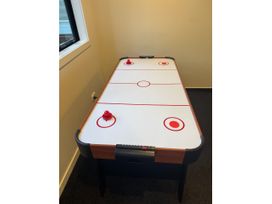 An air hockey table with red pucks and goals in a game room at Estuary Views - Riverhead Holiday House Riverhead