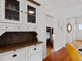 A hallway with a white cabinet on the left and a bunk bed seen through an open door at The Wallnutt Nook - Waihi Beach