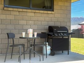 An outdoor area with a grill, table, and chairs at Mountainview Escape - Te Anau