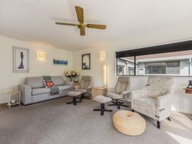 A living room with a sofa chairs a pouffe and a ceiling fan at Tahunanui Shoreside - Nelson Holiday Home in Tahunanui Beach