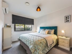 A bedroom with a floral bedspread a blue headboard and bedside tables with lamps at Tahunanui Shoreside - Nelson Holiday Home Tahunanui Beach