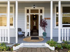 Front porch of a house with a chair a potted plant and an open door at Haere Mai Reefton Heritage Holiday Home in Reefton