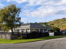 A single story house with a black fence and a large tree beside it at Haere Mai Reefton Heritage Holiday Home in Reefton