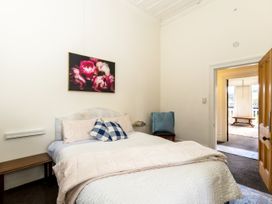 A bedroom with a bed and pillows a wooden bench and a doorway leading to another room at Haere Mai Reefton Heritage Holiday Home in Reefton