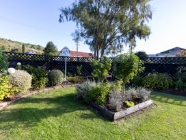 A garden with a black fence two small trees and a raised flower bed at Haere Mai Reefton Heritage Holiday Home in Reefton