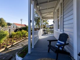 A porch with two black wooden chairs and a garden with plants and flowers at Haere Mai Reefton Heritage Holiday Home in Reefton