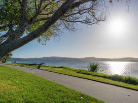 A paved path along a lake with grass and trees on the side at King's Crossing - Your Taupo Getaway in Taupo Central