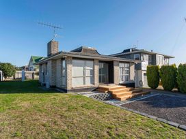 A single-story house with large windows and a wooden front porch surrounded by a lawn at King's Crossing - Your Taupo Getaway in Taupo Central
