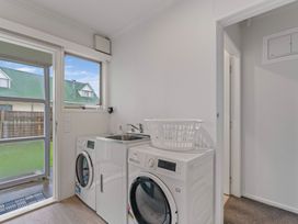 A laundry room with a washing machine dryer laundry basket and a sink at King's Crossing - Your Taupo Getaway Taupo Central