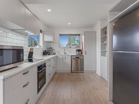 A kitchen with white cabinets a microwave an oven a dishwasher a refrigerator and windows at King's Crossing - Your Taupo Getaway in Taupo Central