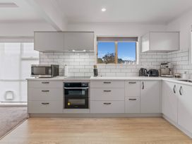 A modern kitchen with grey cabinets white countertops a window microwave oven toaster kettle and coffee machine at King's Crossing - Your Taupo Getaway in Taupo Central