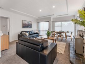 A living room with two black sofas a wooden coffee table a dining table with chairs and a stone fireplace at King's Crossing Your Taupo Getaway Taupo Central
