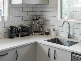 A kitchen countertop with a kettle, toaster, coffee machine, container of ground coffee, soap dispenser, and a sink at King's Crossing - Your Taupo Getaway in Taupo Central