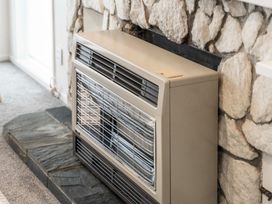 An indoor gas heater installed in front of a stone wall with a slate base at King's Crossing - Your Taupo Getaway in Taupo Central