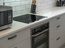 A kitchen counter with a microwave oven a cooktop a knife block and drawers at King's Crossing - Your Taupo Getaway in Taupo Central