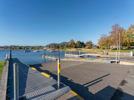 A boat ramp with floating docks and sailboats on a lake with trees and houses in the background at King's Crossing - Your Taupo Getaway in Taupo Central