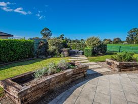 A garden with raised wooden flower beds stone steps and green hedges at Bennett's Bach  Waipu