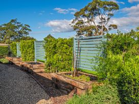 A garden area with wooden planter boxes gravel path and blue wooden slat fences at Bennett's Bach - Waipu Holiday Home in Waipu