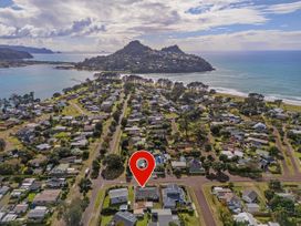 Aerial view of a coastal town with houses and streets near the ocean and hills at Boulevard Bliss Pauanui
