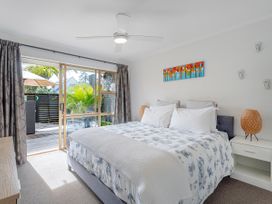 A bedroom with a bed beside sliding glass doors leading to a deck at Boulevard Bliss - Pauanui Holiday Home in Pauanui