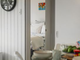 A partial view through a doorway showing a bed with pillows and a blanket in a bedroom and a table with dishes and food in the foreground at Boulevard Bliss - Pauanui Holiday Home in Pauanui