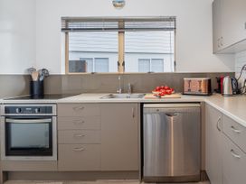 A kitchen with a stove oven dishwasher sink toaster kettle and cutting board with tomatoes at Boulevard Bliss - Pauanui Holiday Home in Pauanui