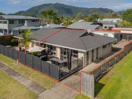 A single-story house with a fenced patio and outdoor furniture surrounded by a yard at Boulevard Bliss - Pauanui Holiday Home in Pauanui