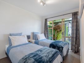A bedroom with two single beds and a glass sliding door leading to an outdoor area at Boulevard Bliss - Pauanui Holiday Home in Pauanui