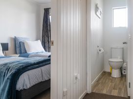 A bedroom with two single beds and a bathroom with a toilet at Boulevard Bliss - Pauanui Holiday Home in Pauanui