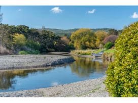 A river with a small boat on the bank surrounded by trees and hills at Peaceful Outlook - Hatepe Holiday Home in Hatepe