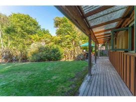A wooden deck with a covered roof beside a lawn and dense greenery at Peaceful Outlook - Hatepe Holiday Home in Hatepe