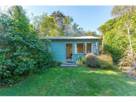 A small blue house with open windows surrounded by greenery and a lawn at Peaceful Outlook - Hatepe Holiday Home in Hatepe
