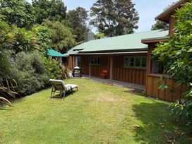 A garden with a chair and table next to a barbecue grill at Peaceful Outlook - Hatepe Holiday Home Hatepe