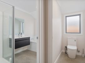 A bathroom with a shower and sink on one side and a separate toilet room with a window at Tide and Tranquility - Whitianga Holiday Home in Whitianga