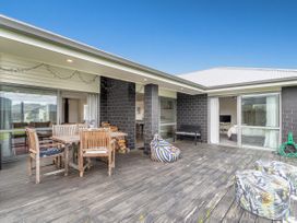 An outdoor deck with wooden table and chairs a bean bag and two floral ottomans at Tide and Tranquility - Whitianga Holiday Home in Whitianga